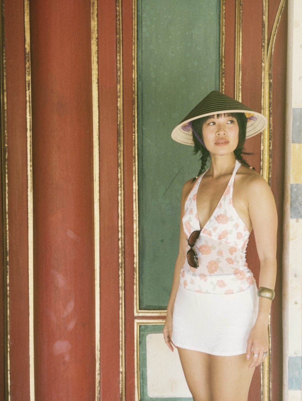 Thu Vu wearing a nón lá in front of red and green architectural panels